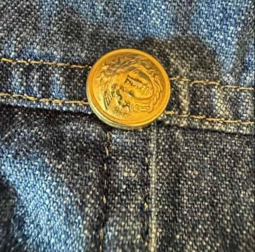 bottone in metallo dorato con l'iconico motivo della Medusa in rilievo di Gianni Versace