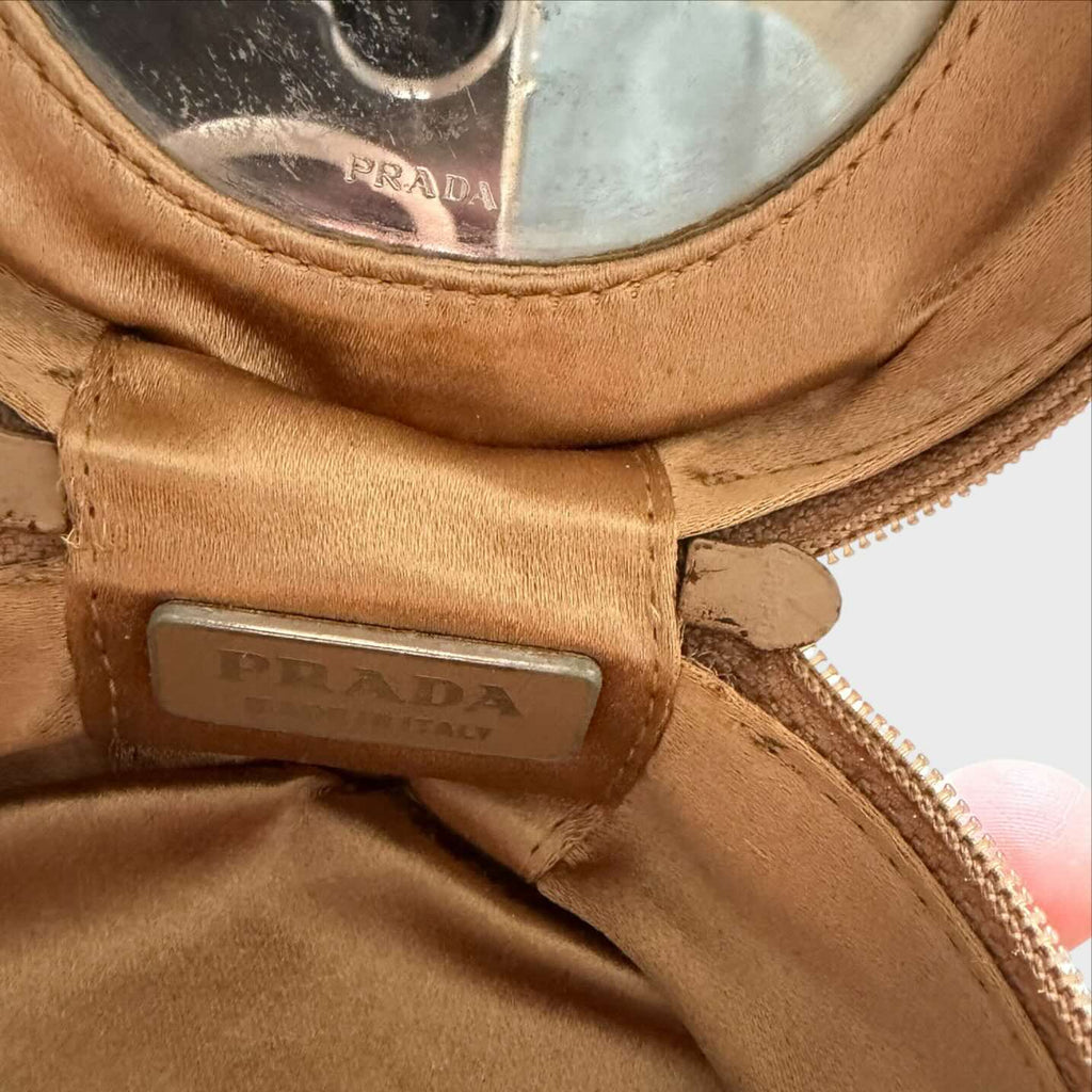 Placchetta in metallo con logo Prada . Specchio con logo Prada
